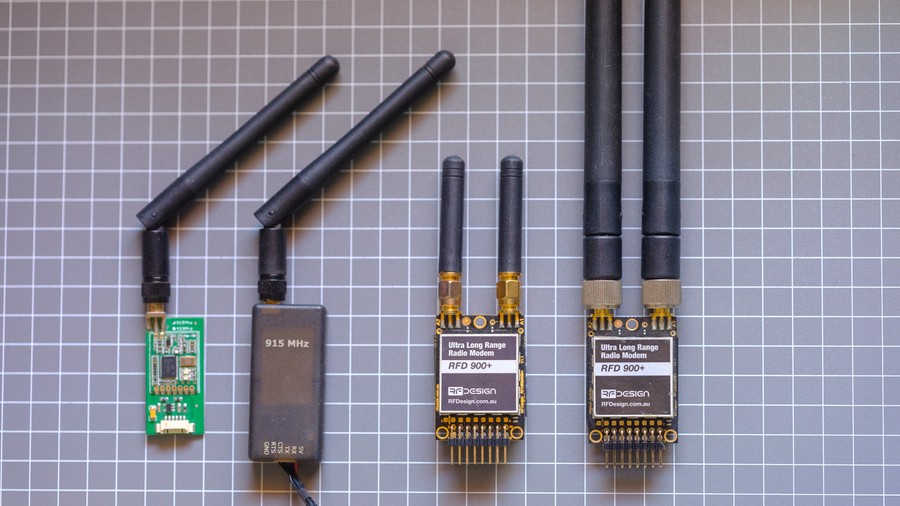 Small green PCB radio with antenna, larger black RFD900 radio module with larger antennas